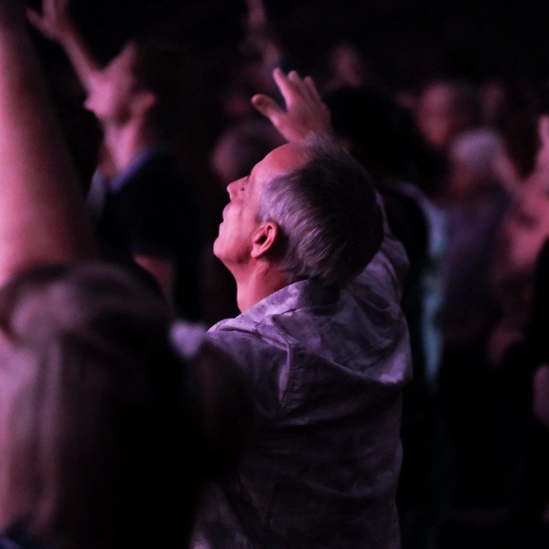 man in gray shirt raising his hands